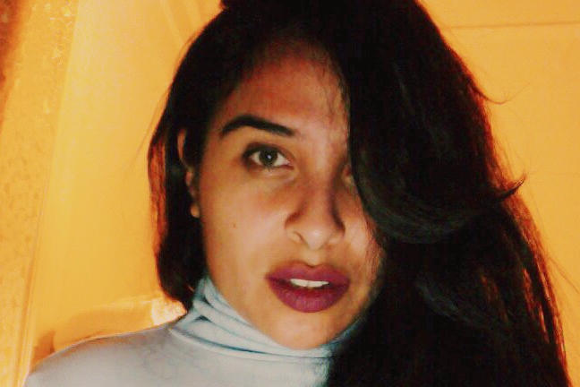 photo of the creative. femme individual with long dark hair staring into the camera.